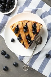 Photo of Slice of delicious homemade blueberry pie served on grey table, flat lay