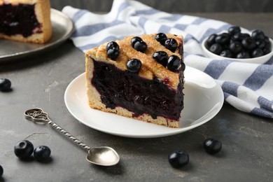 Photo of Slice of delicious homemade blueberry pie served on grey table, closeup