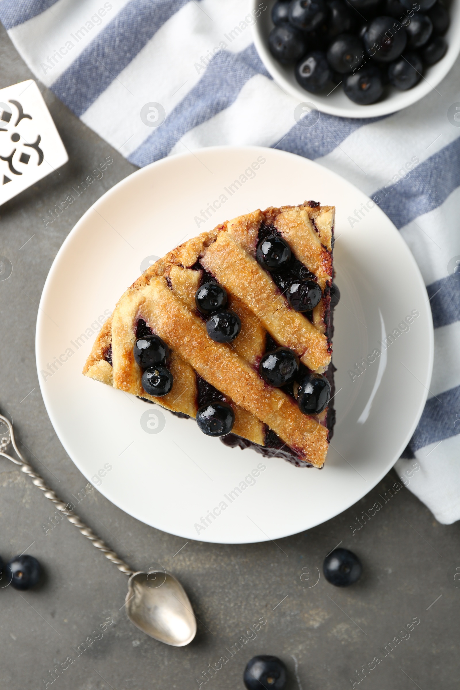 Photo of Slice of delicious homemade blueberry pie served on grey table, flat lay