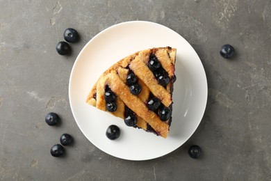 Photo of Slice of delicious homemade blueberry pie served on grey table, flat lay