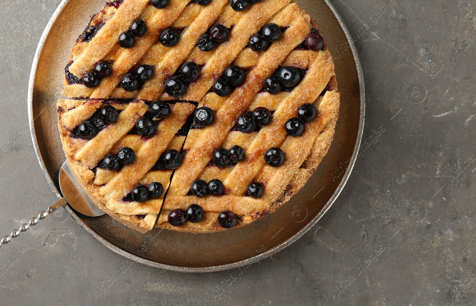 Photo of Cut homemade blueberry pie on grey table, top view