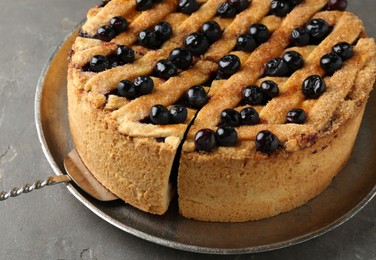 Photo of Taking slice of homemade blueberry pie on grey table, closeup