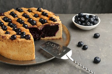 Photo of Cut homemade blueberry pie on grey table, closeup