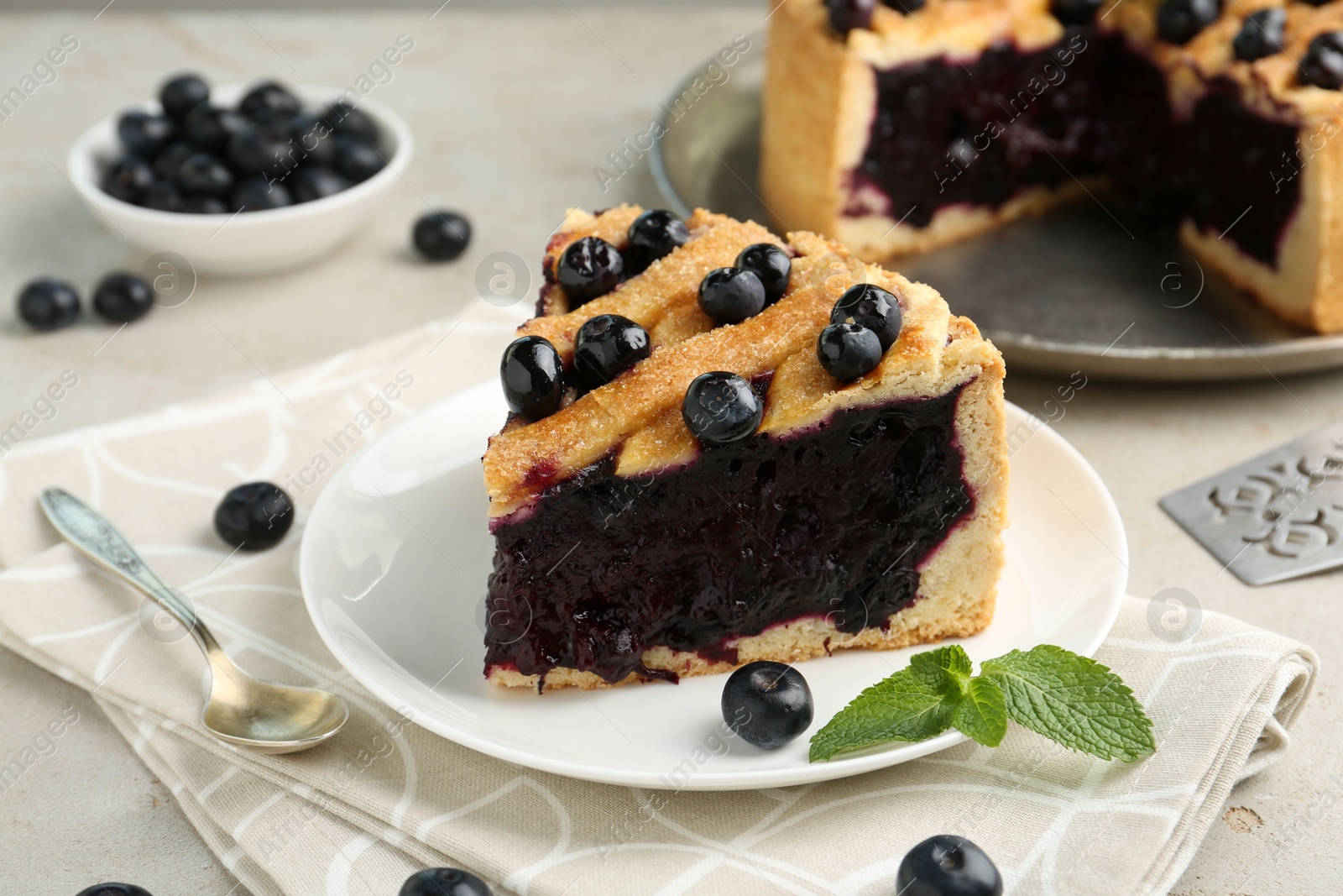 Photo of Slice of delicious homemade blueberry pie served on light table, closeup