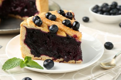 Photo of Slice of delicious homemade blueberry pie served on light table, closeup