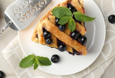 Photo of Slice of delicious homemade blueberry pie served on light table, top view