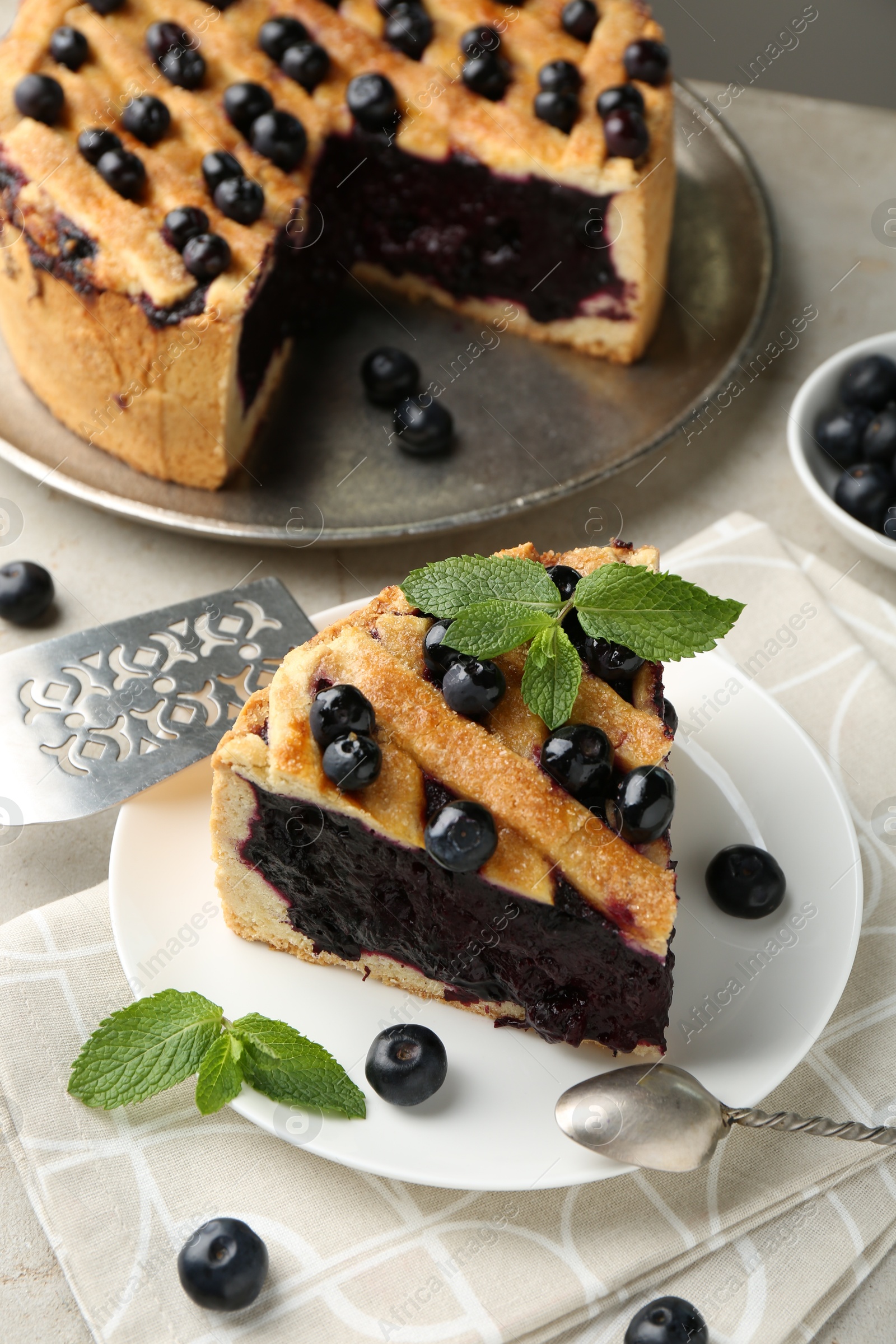 Photo of Slice of delicious homemade blueberry pie served on light table, closeup