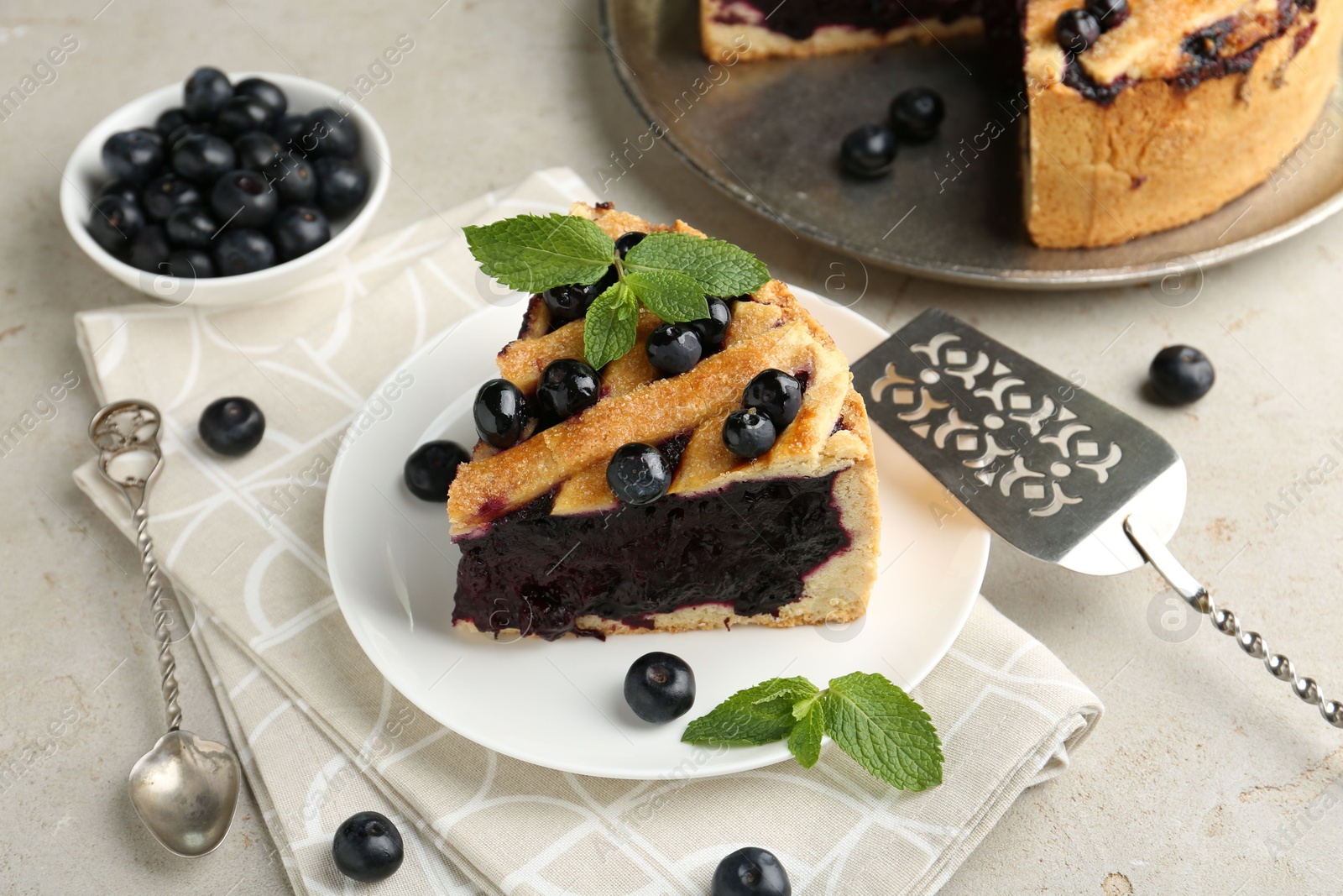 Photo of Slice of delicious homemade blueberry pie served on light table, closeup