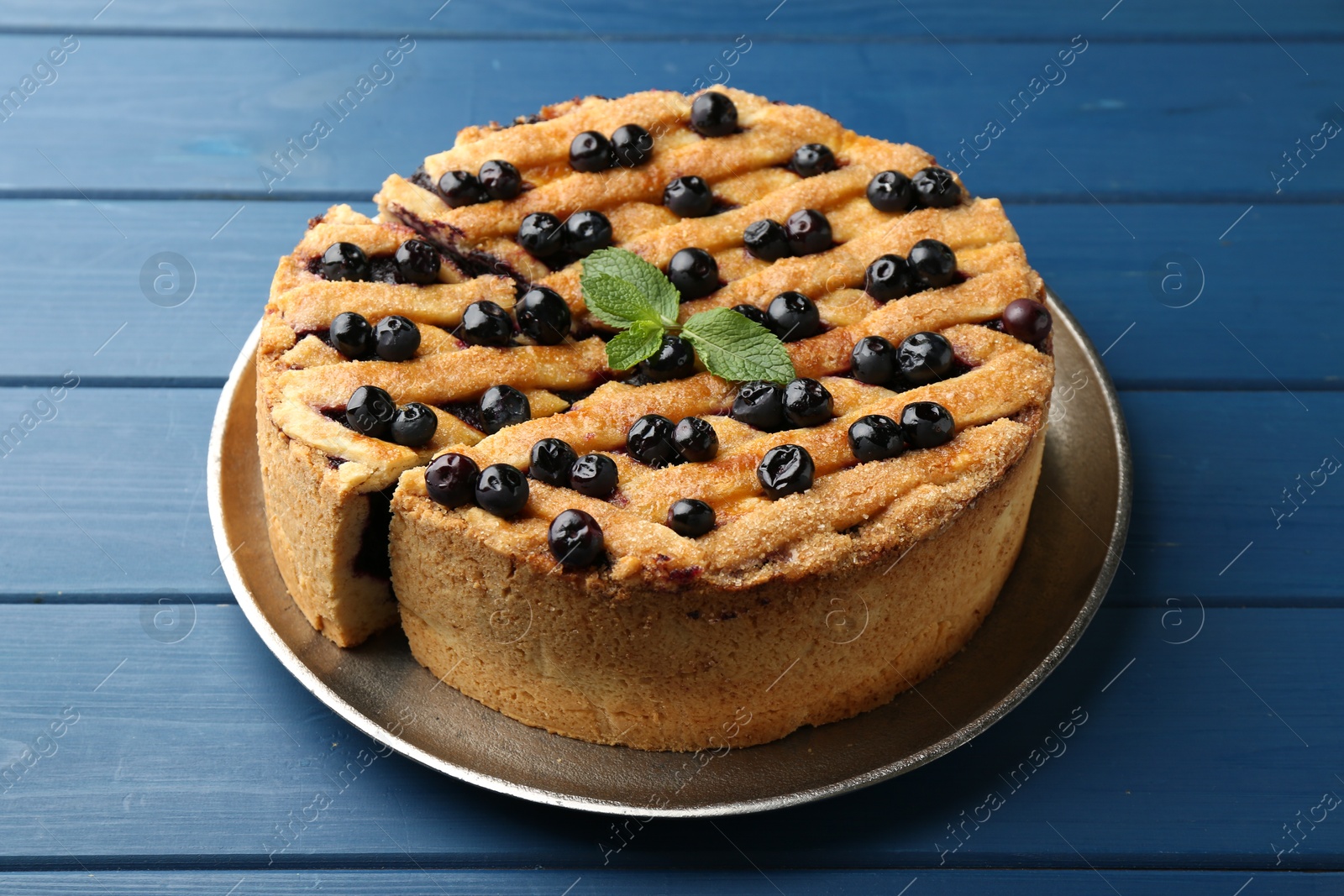 Photo of Cut homemade blueberry pie on blue wooden table, closeup