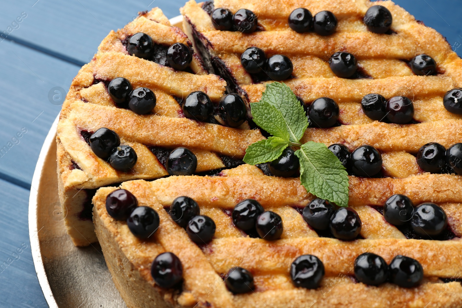 Photo of Cut homemade blueberry pie on blue wooden table, closeup