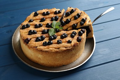 Photo of Taking slice of homemade blueberry pie on blue wooden table, closeup