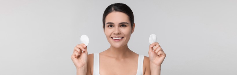 Young woman with cotton pads on light grey background. Banner design