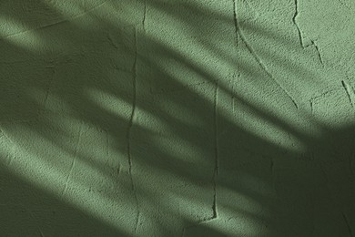 Image of Light and shadows falling on sage color textured wall