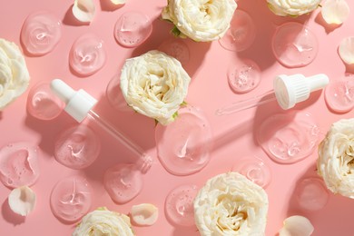 Photo of Beautiful rose flowers, pipettes and drops of cosmetic serum on pink background, flat lay