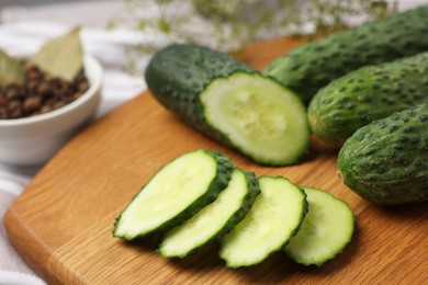 Photo of Fresh whole and cut cucumbers on table, closeup