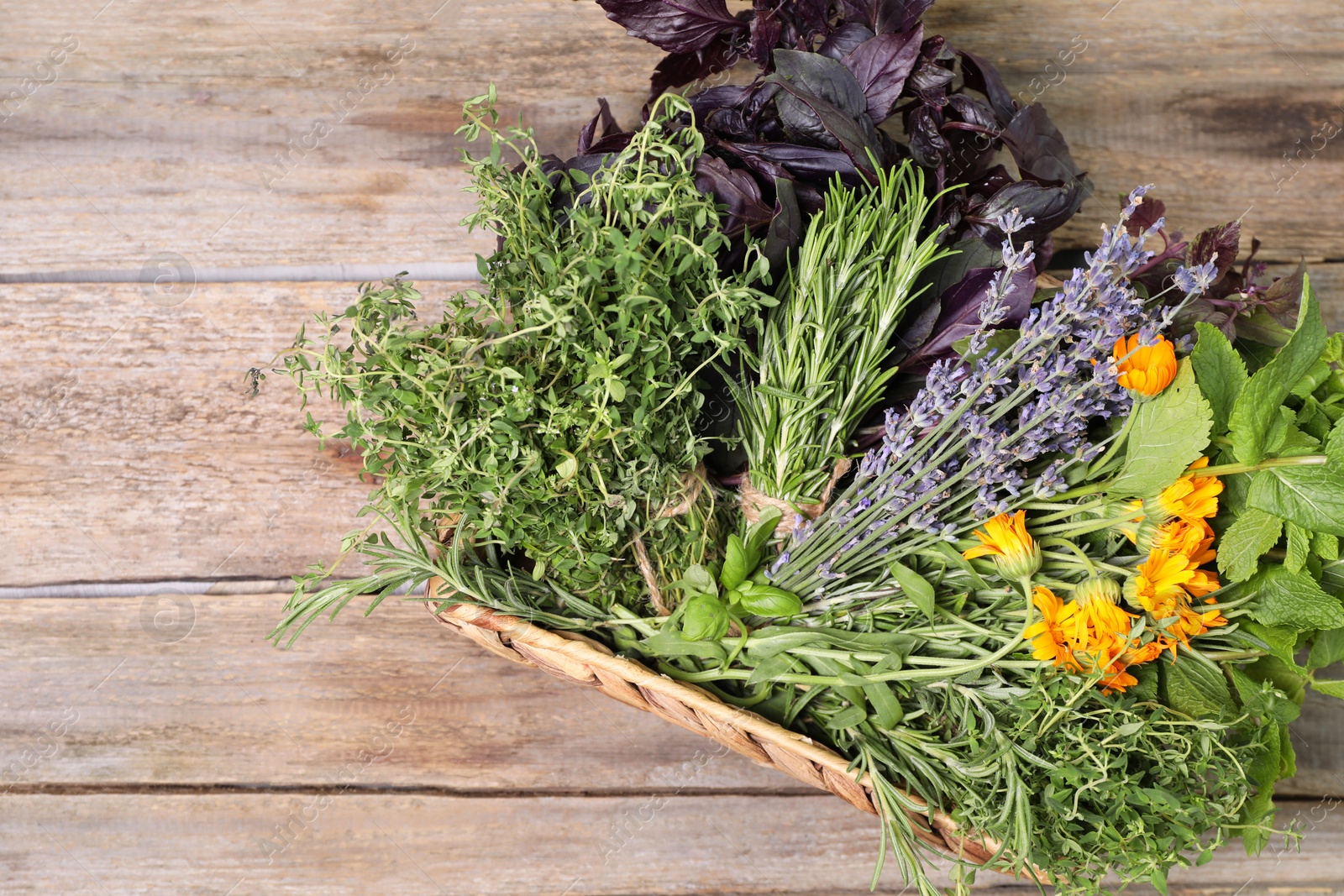 Photo of Different aromatic herbs in basket on wooden table, top view