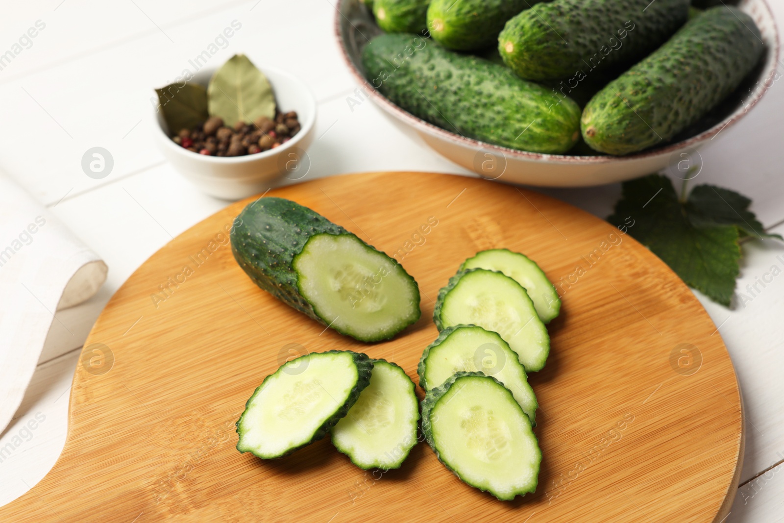 Photo of Fresh whole and cut cucumbers with spices on white wooden table