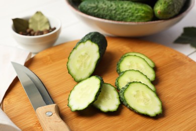 Photo of Fresh cut cucumber and knife on white table, closeup