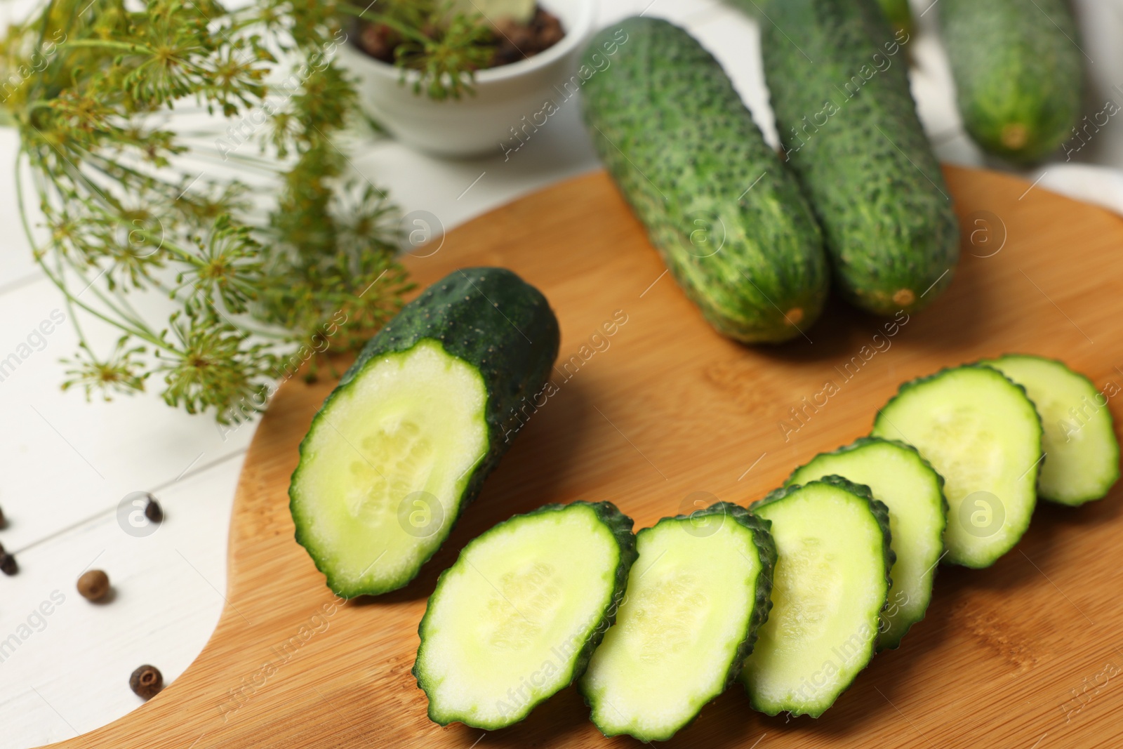 Photo of Fresh whole and cut cucumbers with spices on white wooden table, closeup