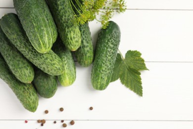 Photo of Fresh green cucumbers and spices on white wooden table, above view