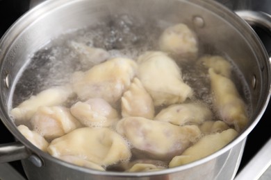 Photo of Preparing Ukrainian dumplings (varenyky) in pot, closeup