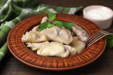 Photo of Traditional Ukrainian dumplings (varenyky) with cherries served on wooden table, closeup