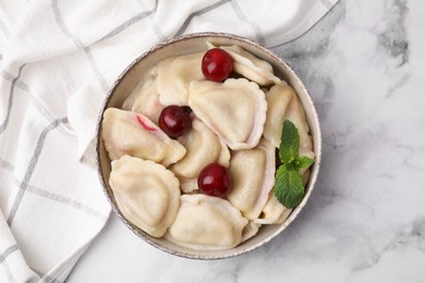 Photo of Traditional Ukrainian dumplings (varenyky) with cherries served on white marble table, top view