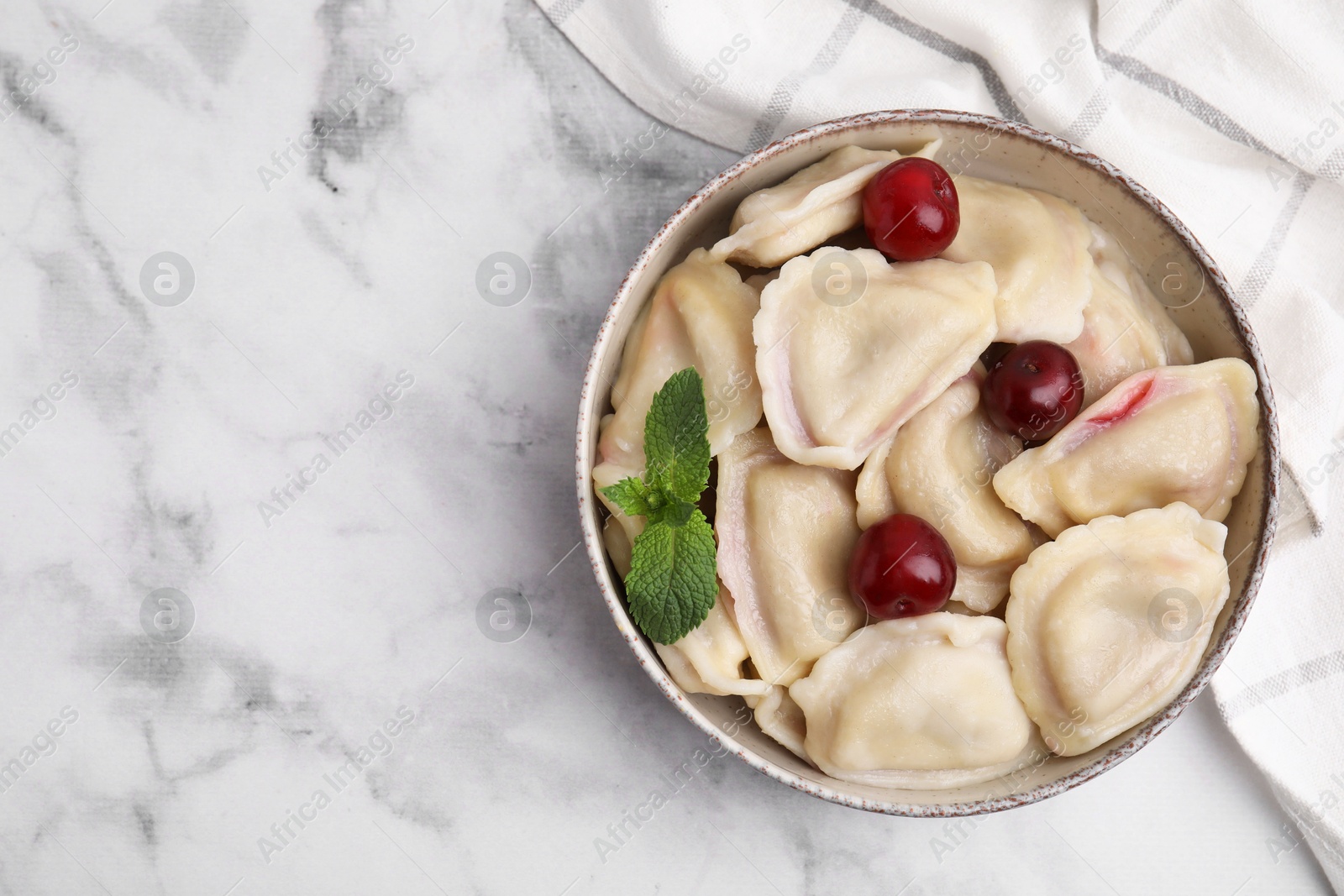 Photo of Traditional Ukrainian dumplings (varenyky) with cherries served on white marble table, top view. Space for text