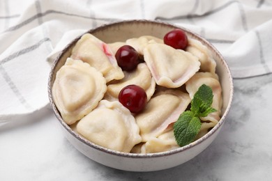 Photo of Traditional Ukrainian dumplings (varenyky) with cherries served on white marble table, closeup