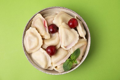 Traditional Ukrainian dumplings (varenyky) with cherries on green background, top view