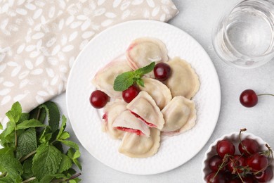 Photo of Traditional Ukrainian dumplings (varenyky) with cherries served on light table, flat lay