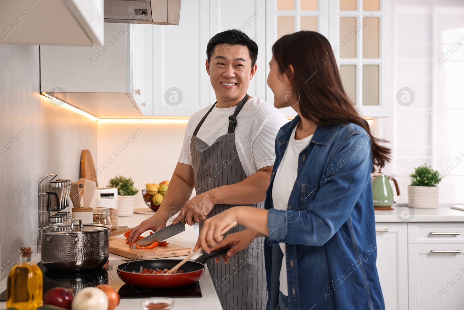 Photo of Happy lovely couple cooking together in kitchen