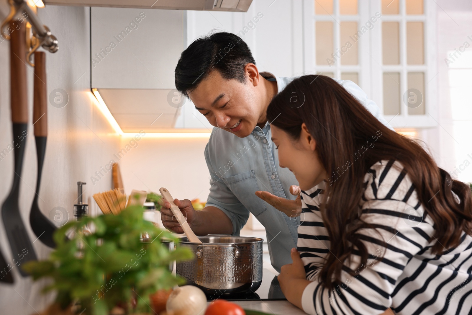 Photo of Happy lovely couple cooking together in kitchen