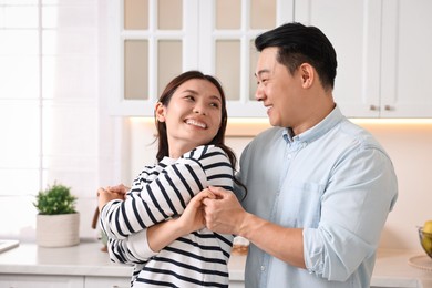 Happy lovely couple dancing together in kitchen