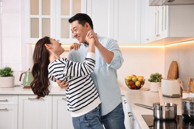 Happy lovely couple dancing together in kitchen