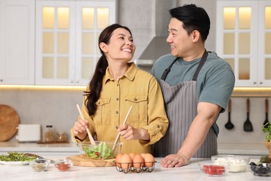 Photo of Happy lovely couple cooking together in kitchen