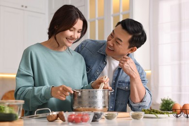 Photo of Happy lovely couple cooking together in kitchen