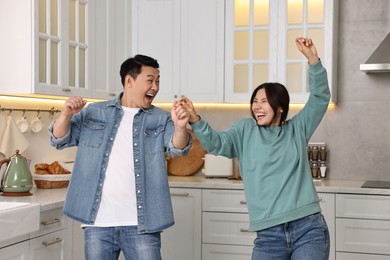 Happy lovely couple dancing together in kitchen