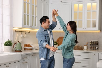 Photo of Happy lovely couple dancing together in kitchen