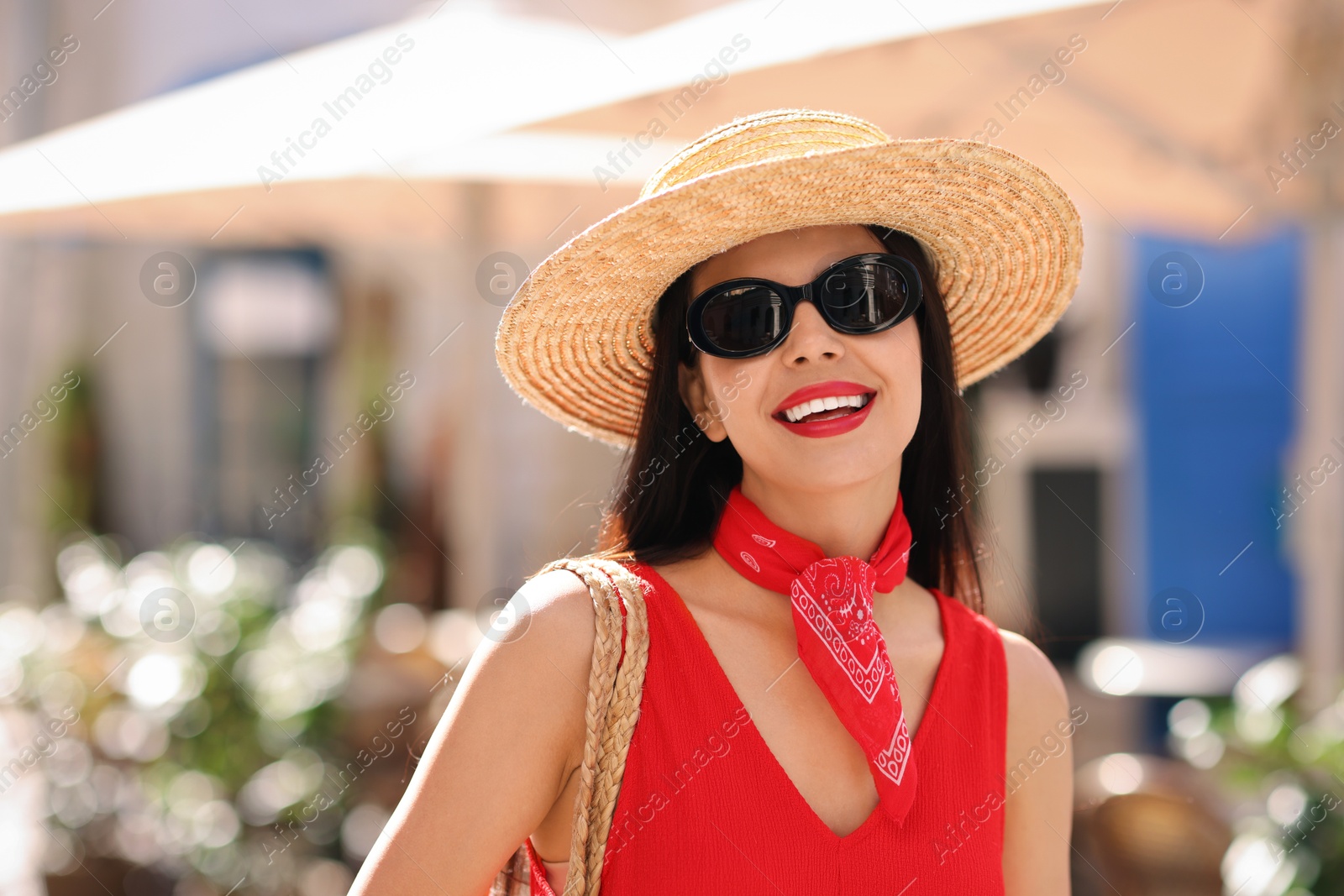 Photo of Smiling young woman in stylish hat and sunglasses on city street