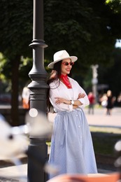 Photo of Smiling young woman in stylish hat and sunglasses on city street