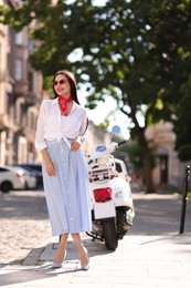 Smiling young woman in stylish sunglasses on city street