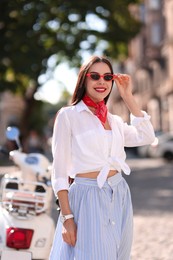 Smiling young woman in stylish sunglasses on city street