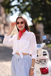 Photo of Smiling young woman in stylish sunglasses on city street