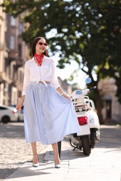 Photo of Smiling young woman in stylish sunglasses on city street