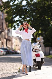 Smiling young woman in stylish sunglasses on city street