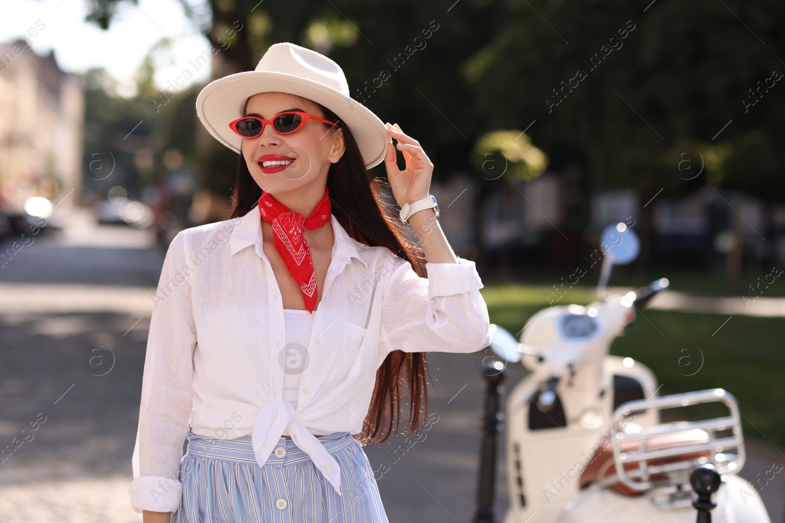 Photo of Smiling young woman in stylish hat and sunglasses on city street