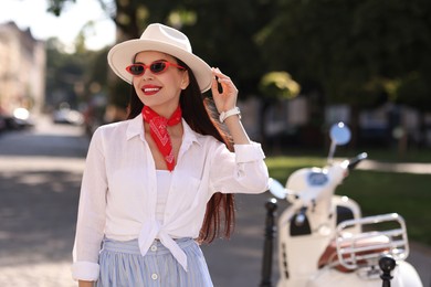 Photo of Smiling young woman in stylish hat and sunglasses on city street