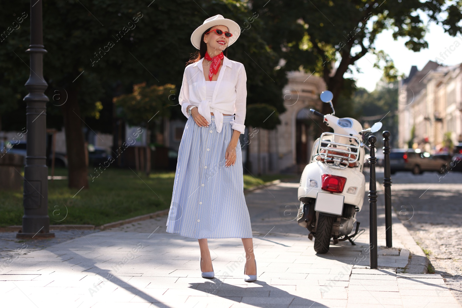 Photo of Smiling young woman in stylish hat and sunglasses on city street