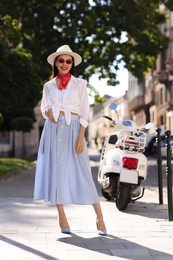 Photo of Smiling young woman in stylish hat and sunglasses on city street